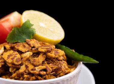 Close Up Of Healthy Flattened Bengal Chana Daal Chatpata Namkeen Masala Chana Jor Zor Garam Served With Lemon Tomato Green Chilly And Coriander Leaf. Isolated On Black background With Space For Text